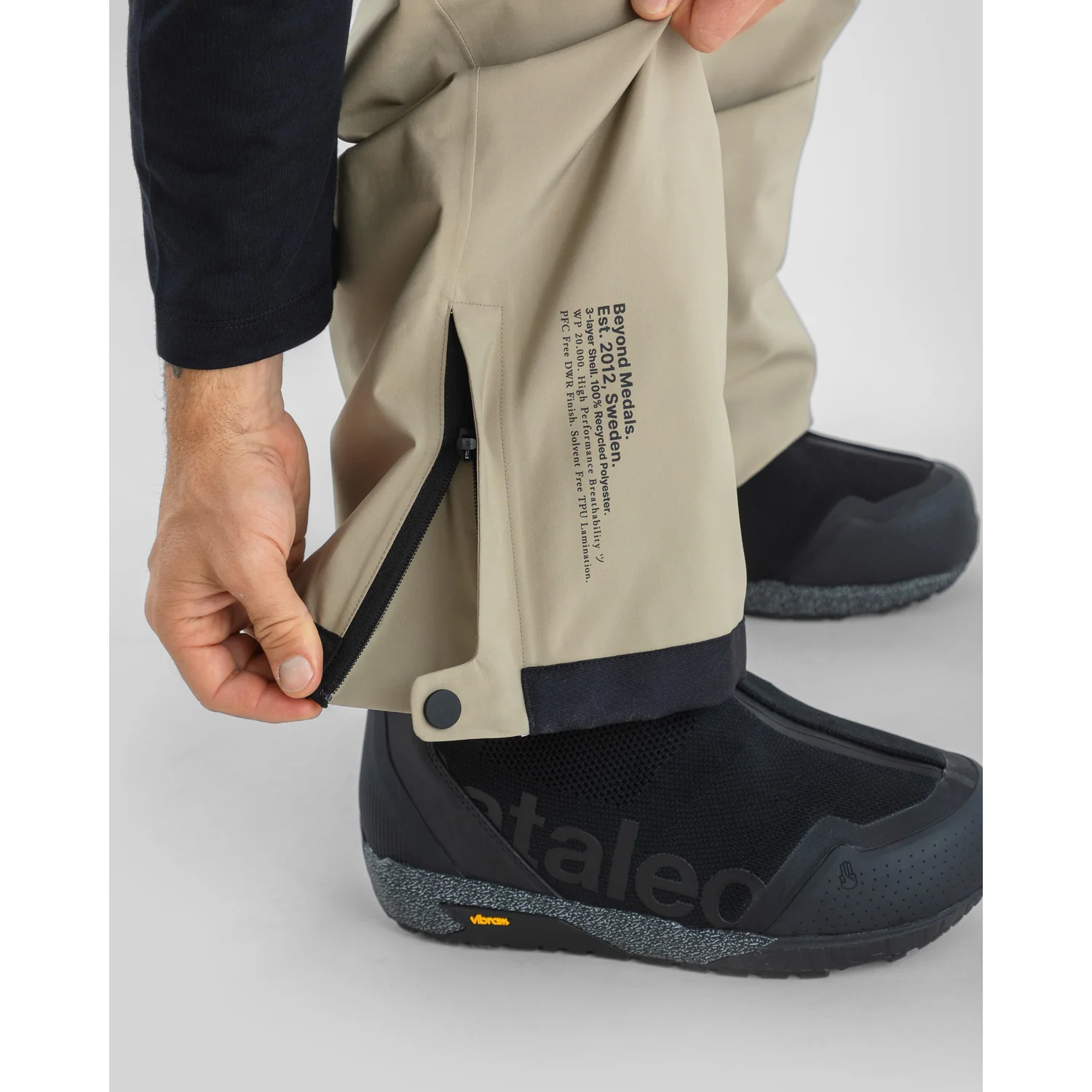 Beige Outdoorhose, Reißverschluss am Bein, verstellbarer Beinabschluss, Dreilagenmaterial, schwarze Schneestiefel