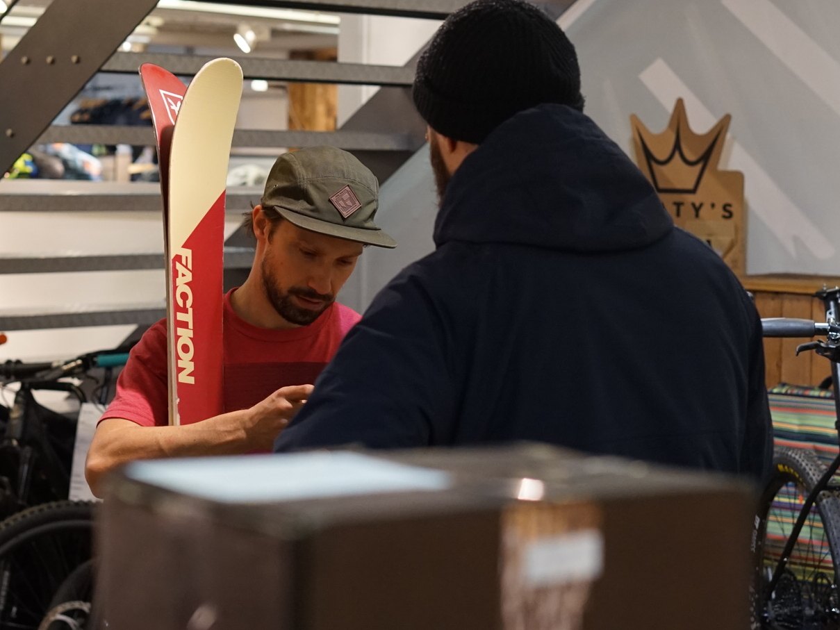 Beratung im Shop: Mitarbeiter und Kunde mit Ski