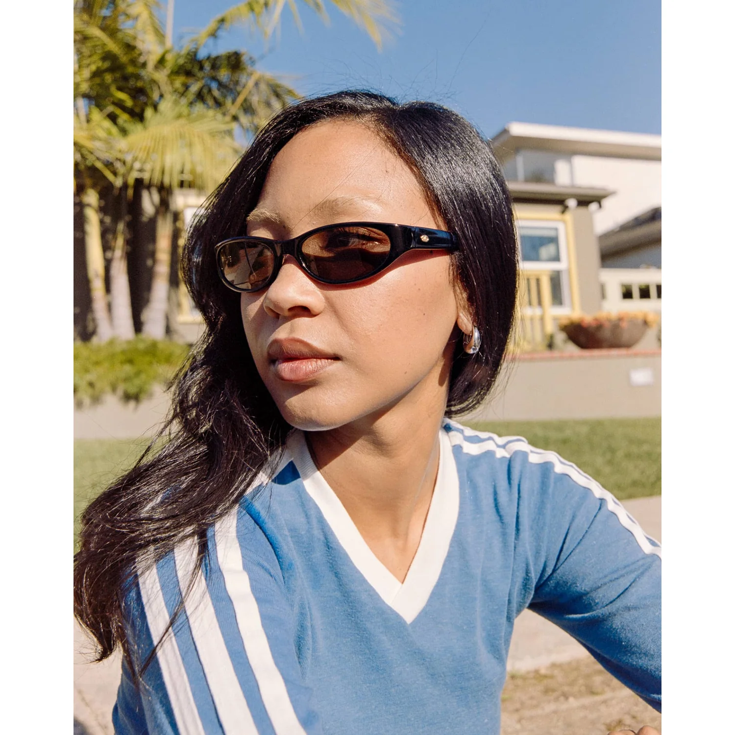 The Mini Funk Polarized Sonnenbrille, schwarzer Kunststoffrahmen, schmale Gläser, blaues Shirt, V-Ausschnitt