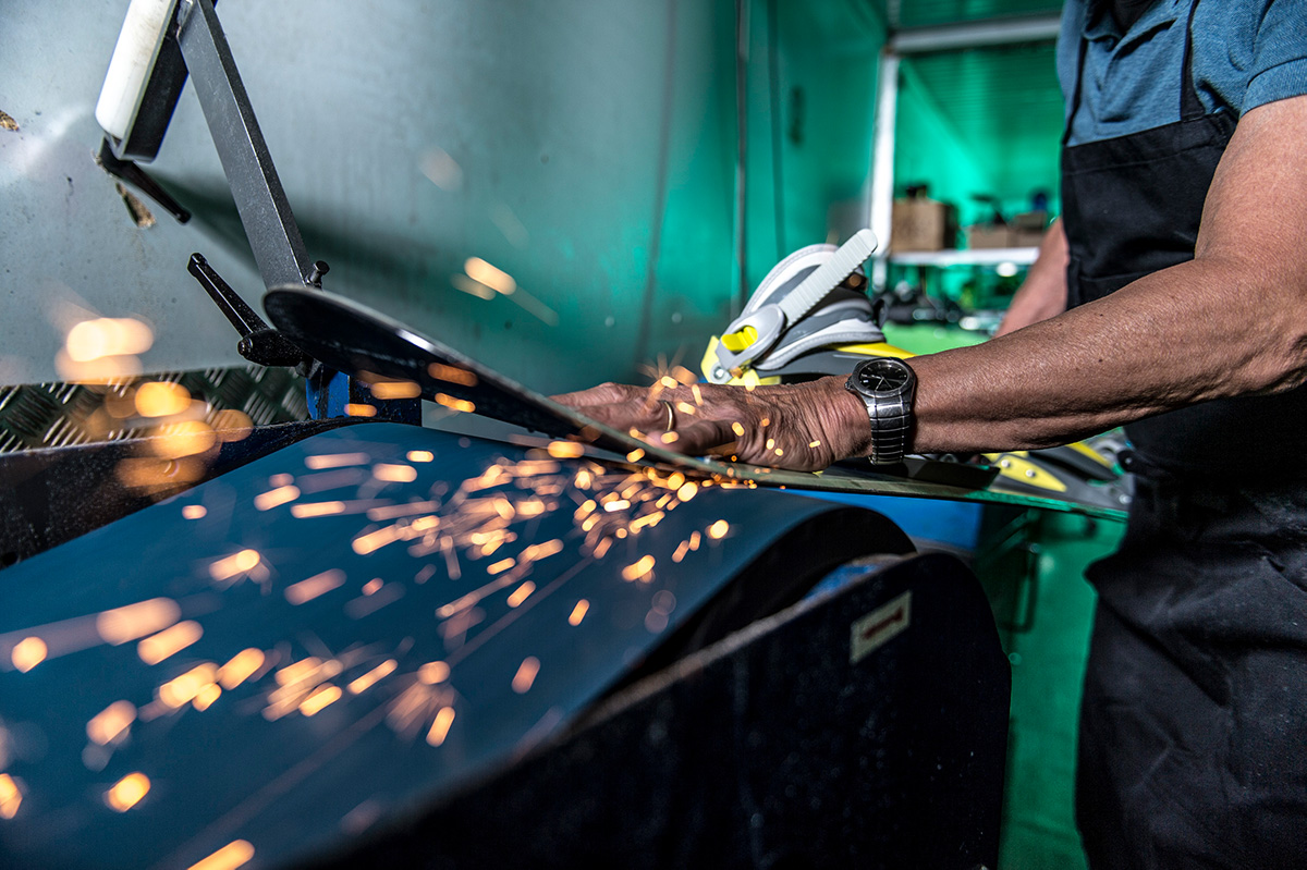 Un employé ponce une planche de snowboard sur la machine d'entretien de l'atelier « Radix »