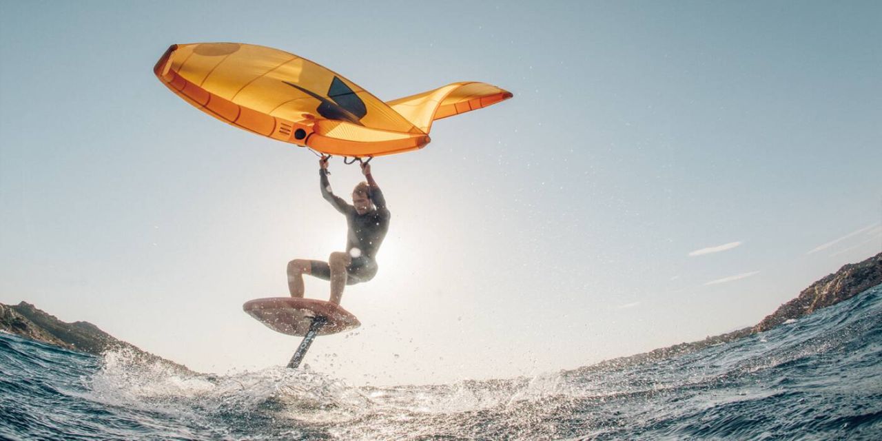 Le wingfoiler vole au-dessus de l'eau avec son wing jaune sur le foil