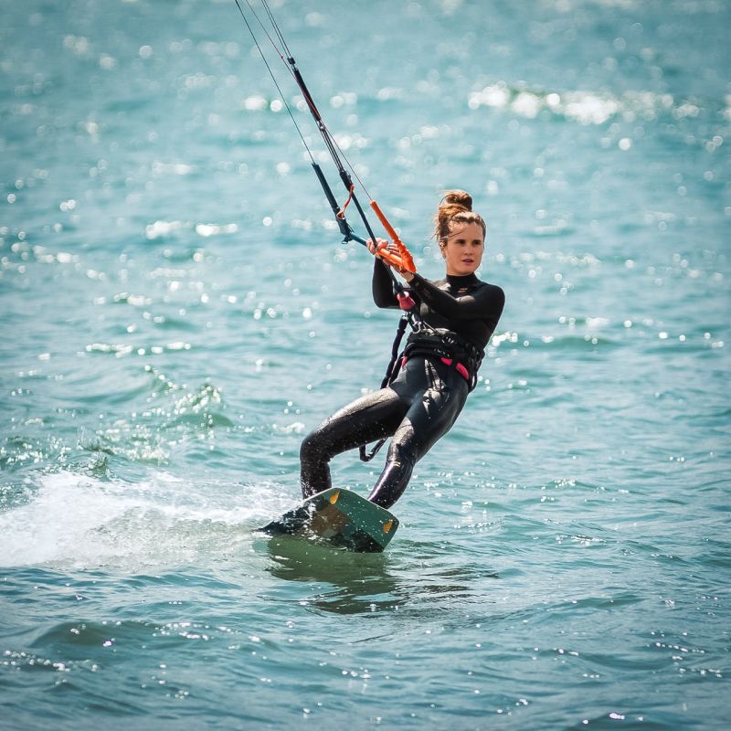 Une kitesurfeuse glisse sur l'eau avec une planche twintip