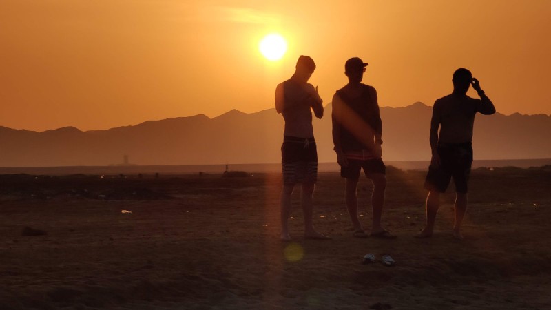 Drei Personen im Sonnenuntergang am Strand